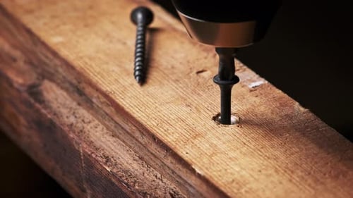 CloseUp of Screw is Unscrewed From a Wood Board with a Screwdriver