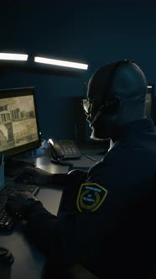 Black Man As Police Officer Using Pc and Watching Surveillance Feed Vertical