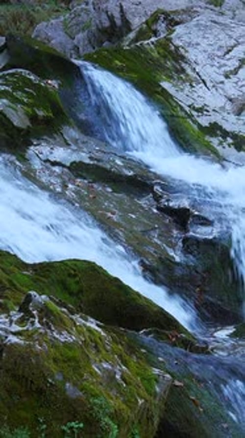 Cascading Waterfall Flowing Over Rocks Covered in Moss