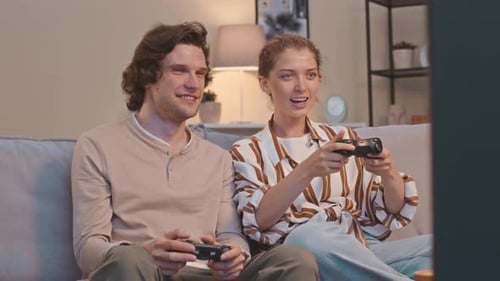 Smiling Couple Playing Video Games on Sofa