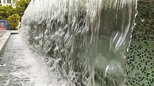 A
água cai de perto ou da fonte para uma pequena piscina na cidade. Câmera lenta