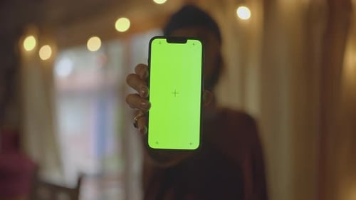 Girl With Beanie Indoors Holds Up Chroma Key 13 Pro With Beautiful Bokeh Lights Background