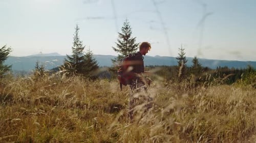 Redhead man on mountain road with backpack having adventure in summer mountains