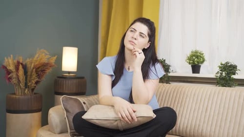 Thoughtful Woman Sitting Cross-Legged on Sofa
