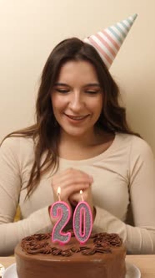 17. The girl is sitting in front of a table with a festive cake, in which a candle in the form of th