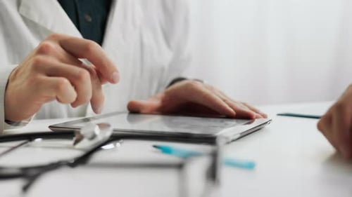 Analysis. A young specialist in a white coat uses modern tablet to enter data in a doctor's waiting