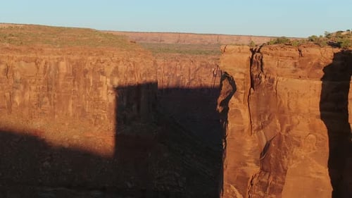 Aerial sunrise flight over dramatic red rock canyon cliffs near Moab Utah
