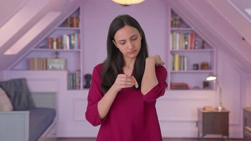 Woman Applies Bandage to Arm Injury Indoors