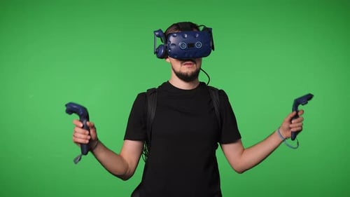 A Man Uses Virtual Reality Glasses to Play in a Studio on a Green Background