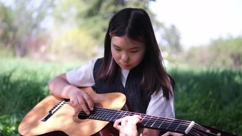 Child Plays Guitar in a Green Field