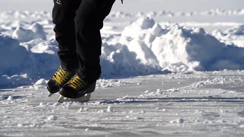 Close up of person ice skating on a sunny frozen lake during Winter.