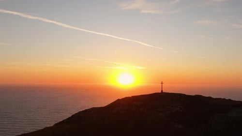 Sunrise Illuminates Cross on Hilltop Overlooking the Ocean