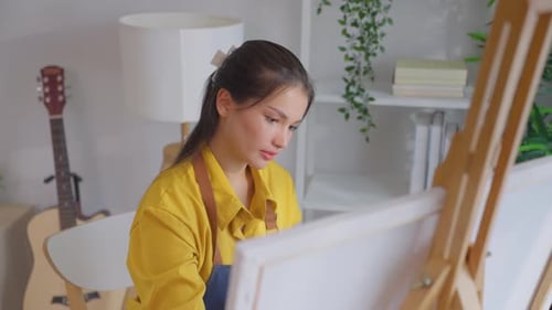Asian young talented woman artist coloring on painting board in house.