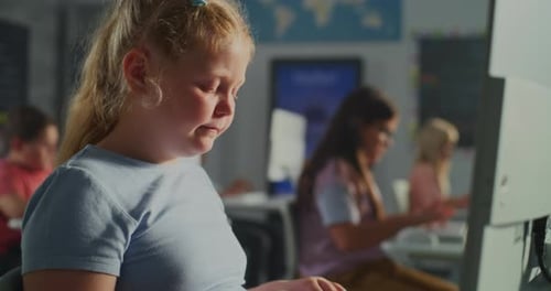 Child Typing on Computer in Classroom with Students