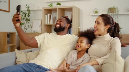 Family Relaxing on Couch, Using Smartphone to Connect