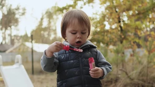 A Joyful Child Happily Enjoying Playing with Bubbles in a Colorful Autumn Park Setting