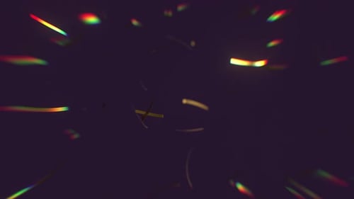 Falling Gold Confetti with soft focus rainbow color rays of light.