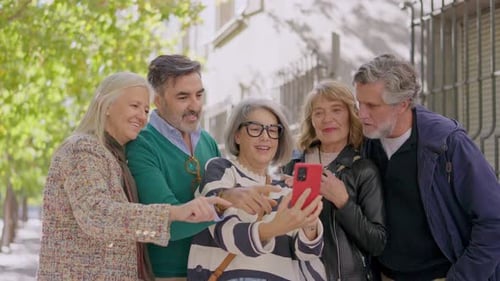 Group of Friends Looking at Cell Phone on Street