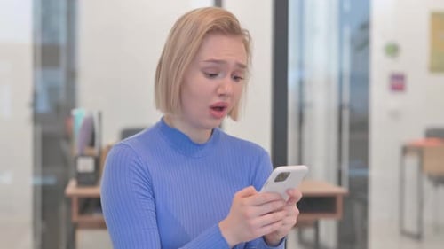 Distraught Young Woman with Phone in Office