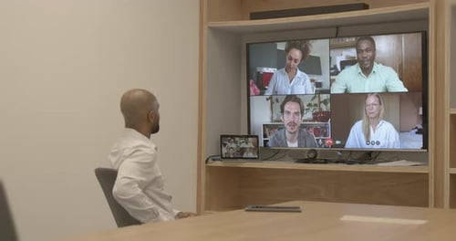 Businessman in an office on a video call with coworkers working from home remotely