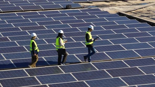 Ingenieure inspizieren ein großes Solarpanel-Kraftwerk