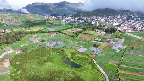 Patchwork Farmland Valley Aerial View Beneath Cloudy Hills And Village