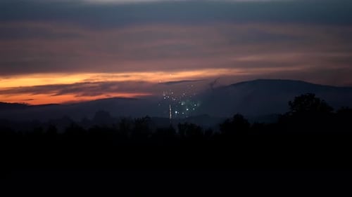 Foto estática em câmera lenta de fogos de artifício estourando e explodindo no céu ao entardecer