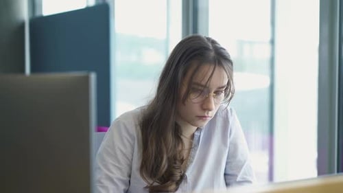 girl works at a computer in a modern office, the girl is studying