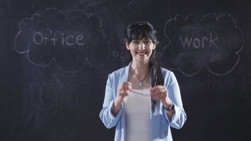 Woman writing Office Worker on blackboard looks at camera with her arms folded.