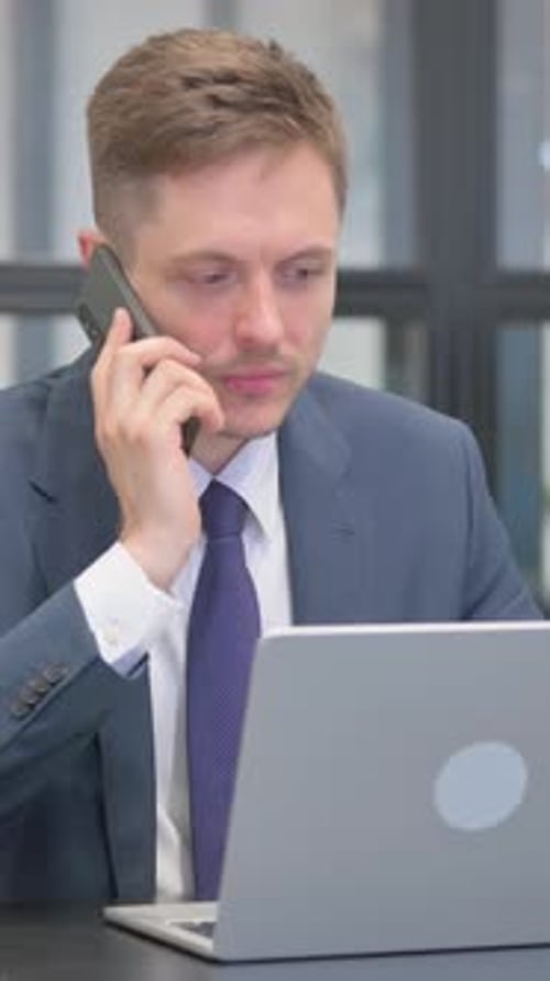 Professional Man Talking on Phone While Using Laptop