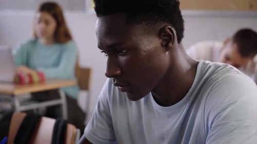 Jeune étudiant afro-américain prenant des notes de cours écrites à la main en classe Concept de l'éducation
