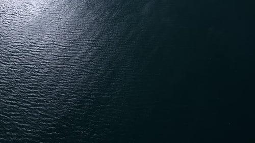Eine Luftaufnahme einer majestätischen Weite des blauen Meeres mit plätschernden Wellen und dem hellen Glitzern der Sonne