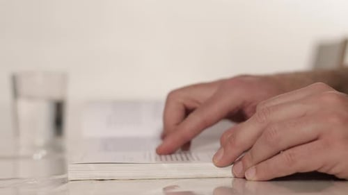 Männliche Hand, die beim Lesen Buchseiten umblättert. Nahaufnahme. Guy liest Buch 4k
