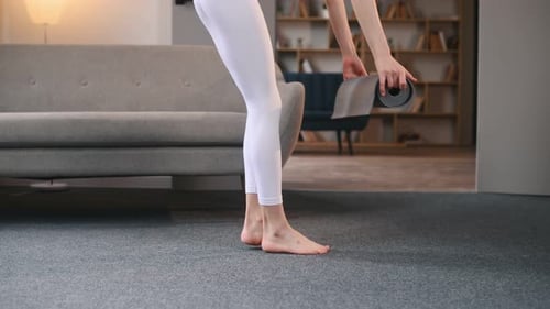 Rolling off the mat. Young woman with slim body type doing yoga at home