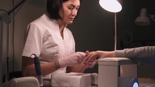 Woman Does Manicure in Nail Salon Workplace
