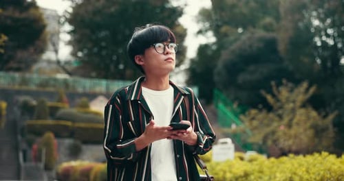 Young Adult Using Mobile Phone in City Park