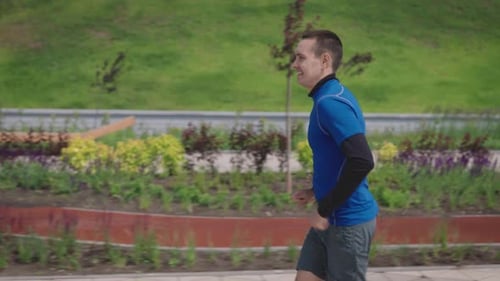 A Young Athletic Man Runs Through a Landscaped and Green Park Sports Lifestyle to Maintain Tone and