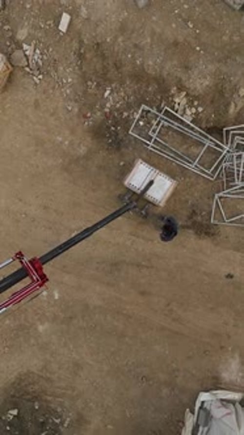 Vertical Video Construction Site Buzz Aerial Perspective of Crane Unloading Builders in Motion