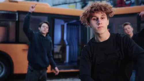 Young Male Dancers Executing Dynamic Street Choreography Beside Orange Bus Showcasing Urban Dance