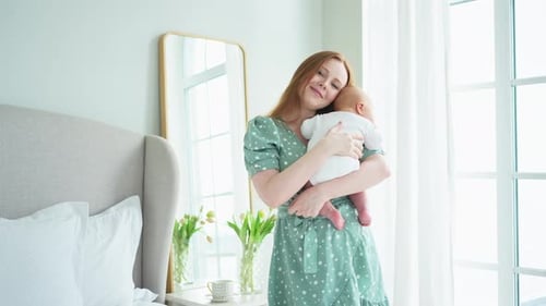 Woman Holds Baby in Bright, Modern Bedroom
