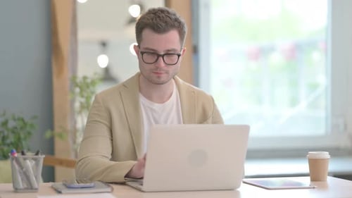 Young Man Celebrating Success at Office Laptop