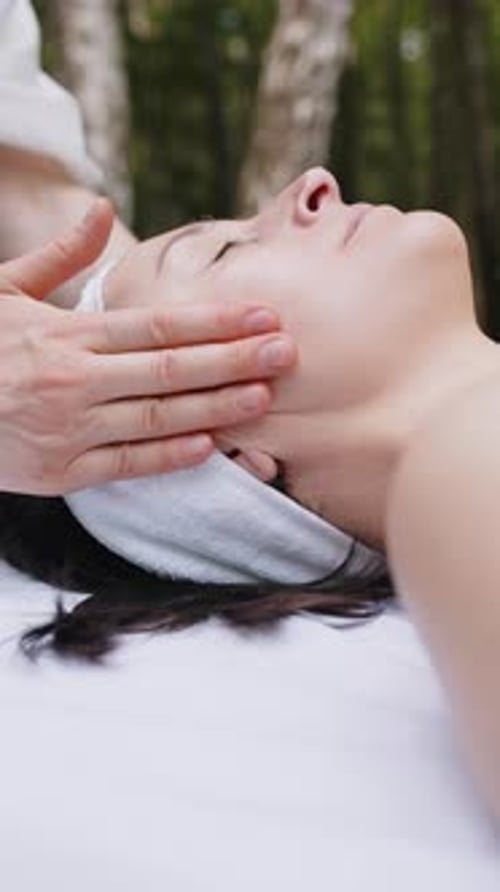 Médica terapeuta fazendo massagem facial relaxante no spa com as mãos ao ar livre na floresta