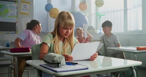 Elementary School Girl Sitting at Desk Happy About Good Grade on Geography or Science Exam