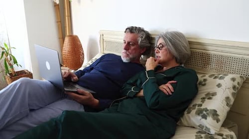 Senior couple using laptop together in bed
