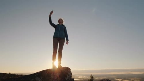 A Traveler Takes Pictures of Himself on Top of a Mountain at Dawn