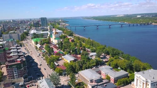 Aerial View of a Sunny City Street with Driving Cars Along the Alley with Green Trees