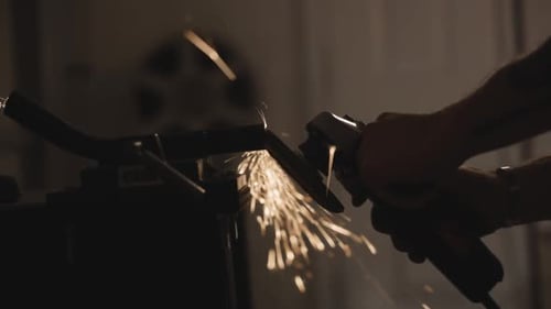 Close backlighting shot of a grinding disc working on metal and many sparks coming out of it.
