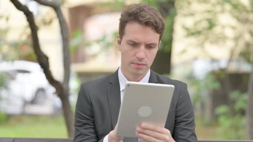 Young Adult Excited at News on Tablet Outdoors