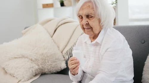 Senior Woman Opening a Pill Bottle on Couch
