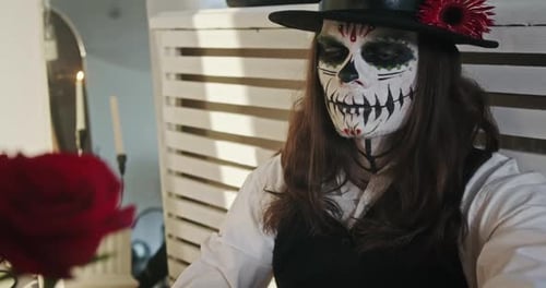 Person with Skull Makeup Holds Red Rose